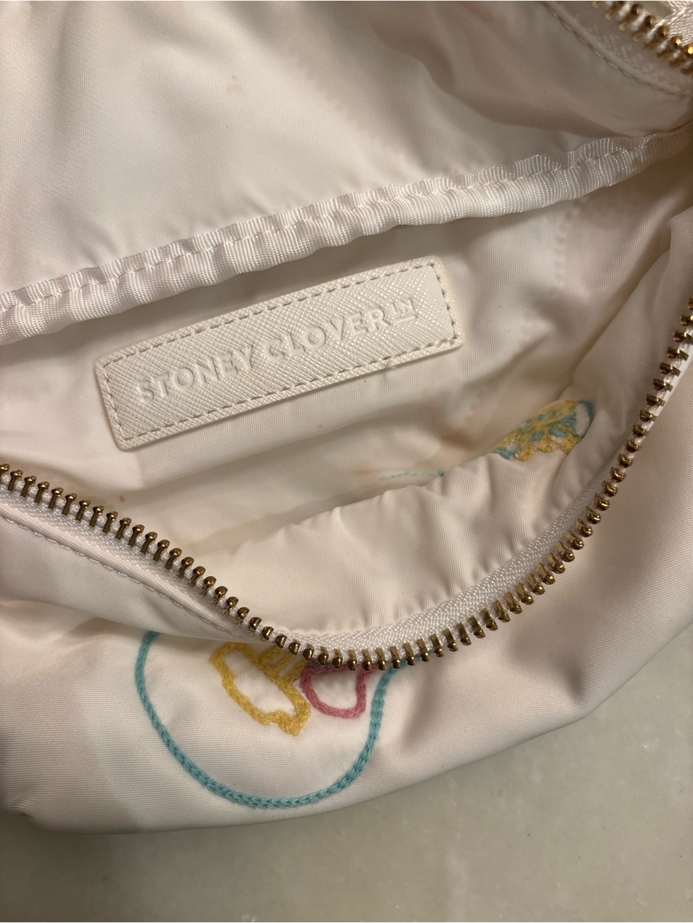 Stoney Clover Lane white pouch with teal, yellow, and pink embroidery